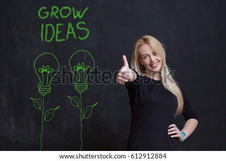 Woman with thump up and drawn two bulbs with written grow ideas. She is satisfied with her work.