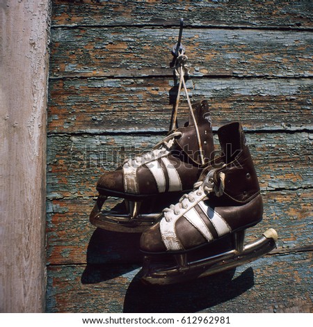 vintage pair of mens  ice skates hanging on a wooden wall