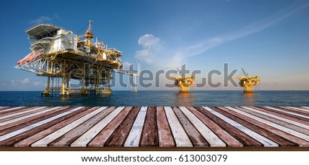 Wooden deck looking out to Offshore Production Platform For Oil and Gas Development, soft focus blur background