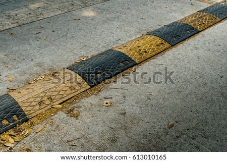 Yellow and black speed bump on concrete road