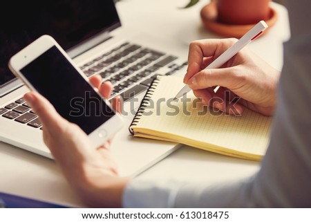 woman writing a note in the workplace. Toned photo