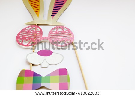 An Easter bunny face with glasses and plaid bow tie made from photo booth props isolated on a white background