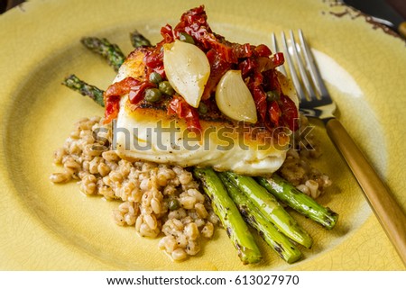 Pan seared halibut fillet over bed farro with grilled asparagus, topped with salsa of red peppers, sundried tomatoes, garlic and capers