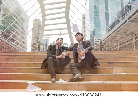 Two stressed business man are sitting sadly at stairs in city.