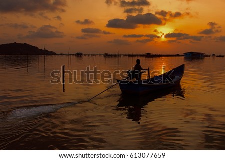 silhouette of fisherman on boat with sunset in the background