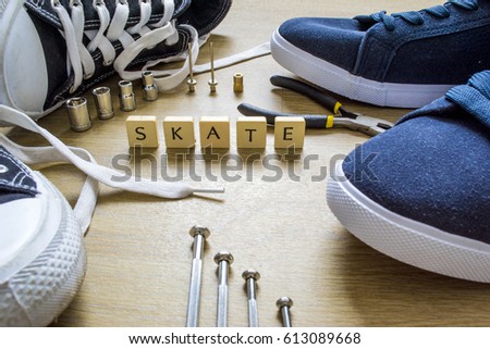 The word "skate" laying on floor next to a pair of sneakers
