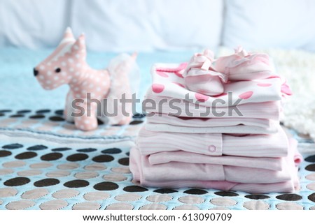 Pile of baby clothes on bed
