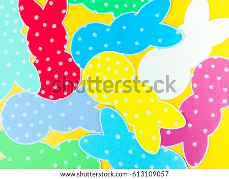 Close-up of colorful paper rabbits silhouette frames against golden background