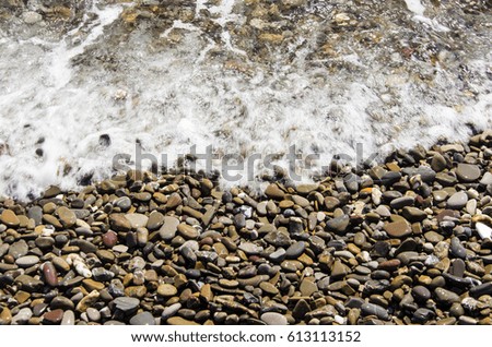 Sea and pebble beach with rocks on a sunny day