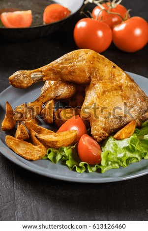 Roasted chicken legs with potato wedges and tomatoes on a plate