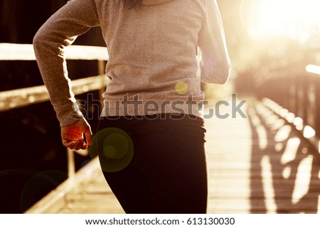Female jogger running in beautiful sunset with a nice flare showing on photo
