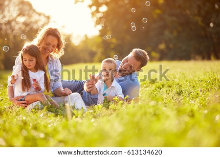 Children in green nature make soap bubble on summer