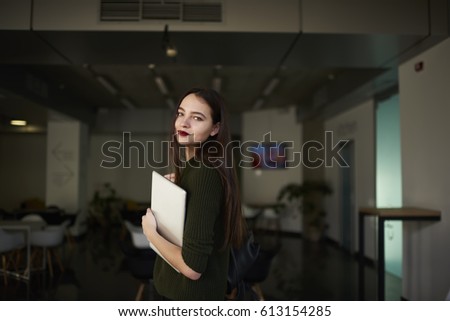 Portrait of attractive young student of design faculty standing in university hall posing for the camera. Successful female architect preparing to work in coworking space with laptop and backpack