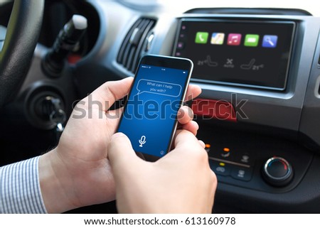 man hand in car holding phone with app personal assistant on screen  Royalty-Free Stock Photo #613160978