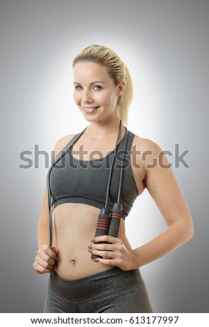 Happy fitness woman with a skipping rope around her neck