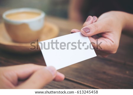 Businessman giving  business card to businesswoman with coffee cup on wooden table background