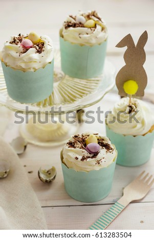 Easter cupcakes with colorful chocolate eggs and rabbit cake topper. Shallow depth of field, copy space.
