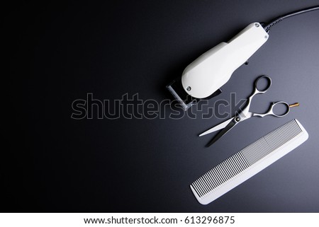 Stylish Professional Barber Scissors, White comb and White electric clippers on black background. Hairdresser salon concept, Hairdressing Set. Haircut accessories. Copy space image, flat lay
