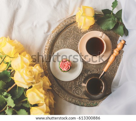 Cup of coffee and cake on the bed with yellow roses