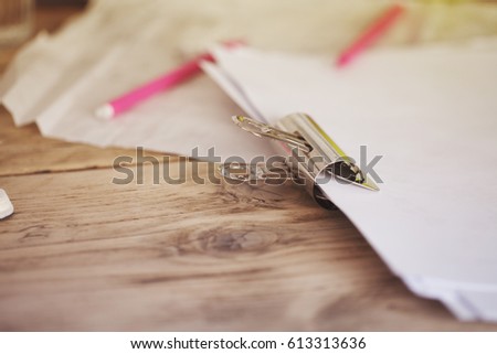 Wide Binder Clip, Paperclip on Some Papers of a Wood Desk with some Pink Mechanical Pencils Warm Toned