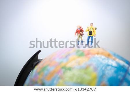 Travelling concepts. Miniature people : Couple travelers mini figures with backpack stand and walking on globe world map balloon