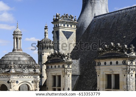 The sandstone walls and towers of an ancient Chambord Castle (Château de Chambord) with gray slate roofs and carved stone royal symbols and other fine details. Chambord, Loir-et-Cher, France.