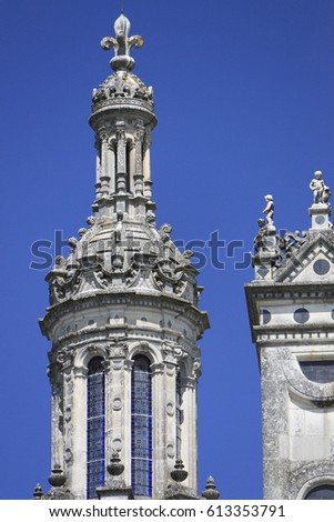 White and gray sandstone towers of an ancient Chambord Castle (Château de Chambord) with its fine carved stone royal symbols and other details on a bright sunny day. Chambord, Loir-et-Cher, France.