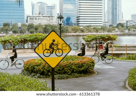 The Yellow Road Sign Bicycle lane at the beautiful park with cyclists, lake and cityscape background