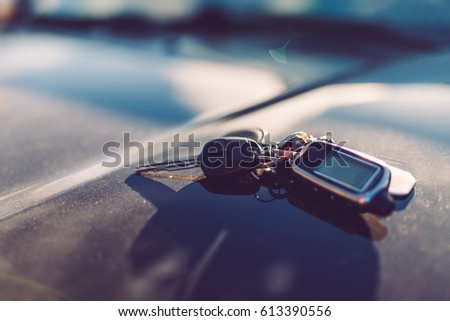 Keys with immobilizer on the car hood in the background of the front Windows. Beautiful spring light and the sun. Warm toned picture, vintage tone.