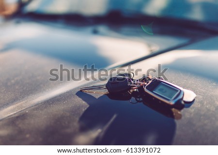 Keys with immobilizer on the car hood in the background of the front Windows. Beautiful spring light and the sun. Toned picture.