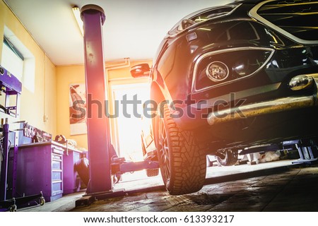 Car in garage of auto repair service shop with special repairing equipment Royalty-Free Stock Photo #613393217