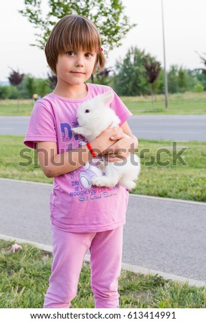 Little girl hugs a rabbit