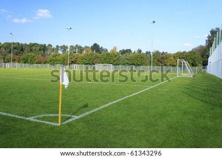 Green empty football field in summer with white flag