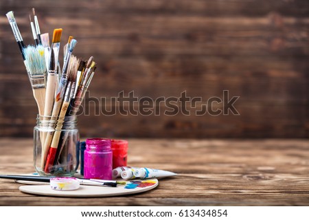 Wooden art palette with tubes of oil paints and a brush. Art and craft tools. Artist's brush, canvas, palette knife. Space for text. Items for children's creativity.Acrylic paint and brushes. Royalty-Free Stock Photo #613434854
