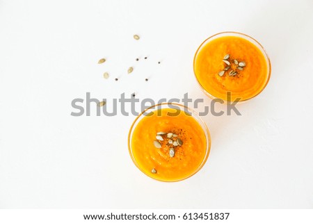 Two plates of pumpkin soup with seeds on a white background with space for your text