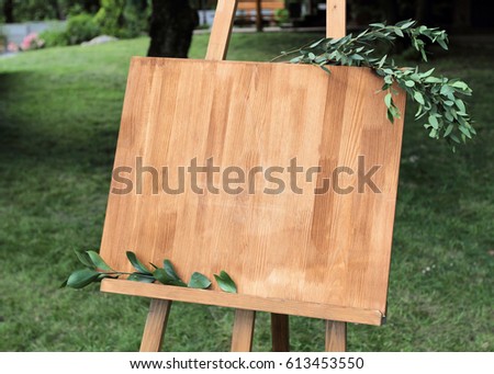 Wooden easel with a board. On the board written white paint - Welcome
