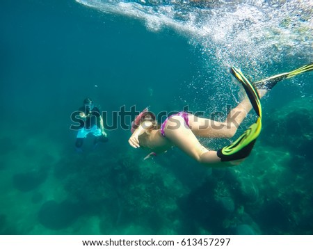 Little girl free diver and her father taking picture with action camera deep underwater. Coral reef Koh Tao island, Thailand. With enough copy space.