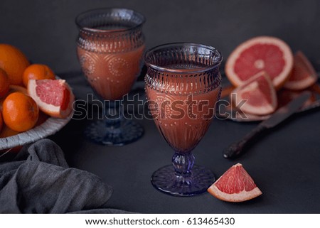 Glass of freshly squeezed grapefruit juice with fresh citrus fruits on dark background. Grapefruits, oranges and tangerines 