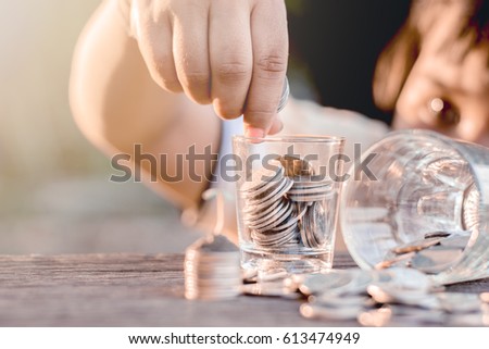 The girl is taking a coin in a small glass placed on a wooden floor.