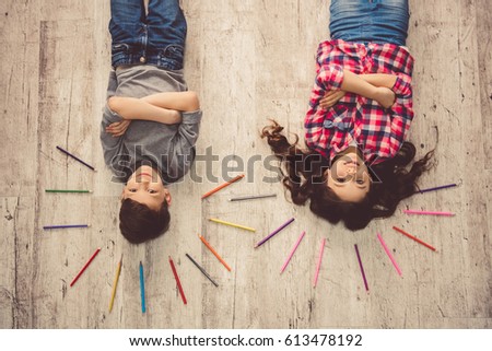 Top view of cute children looking at camera and smiling while lying on the floor at home
