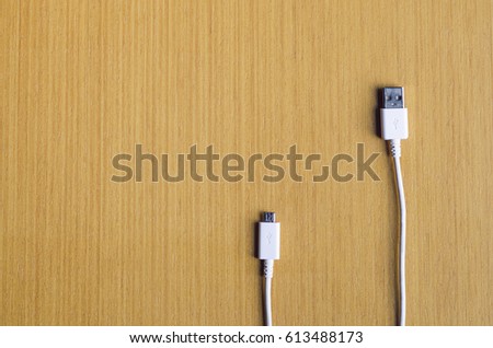 White USB cable with standard and micro port on the wooden background horizontal