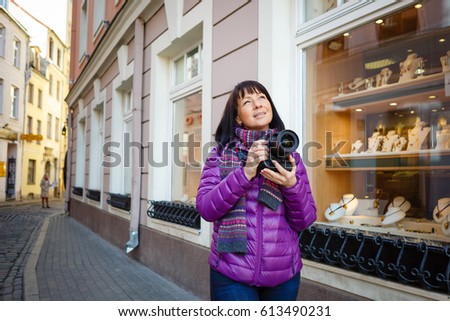 Outdoor spring smiling lifestyle portrait of brunette woman having fun in the old city in Europe. Girl with camera travel photo of photographer taking pictures