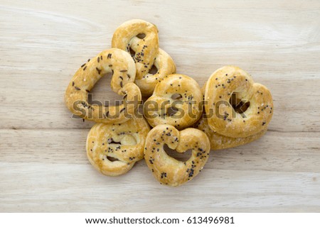 Baked fresh pretzels on wooden table, heart and twisted knot shapes, covered with poppy seeds salt and caraway seeds