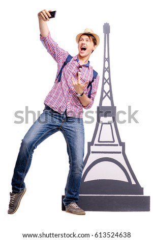 Travel concept. Full length studio portrait of handsome young man taking selfie near eifel tower. Isolated on white.