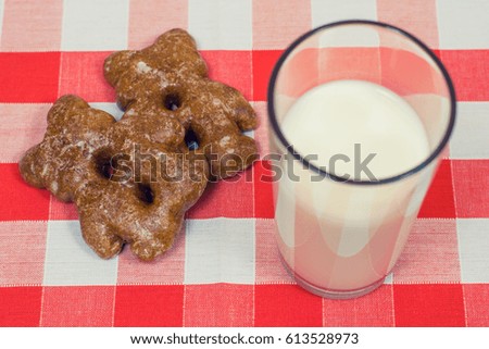 Close up photo of cookies and glass og milk on checkered tablecloth