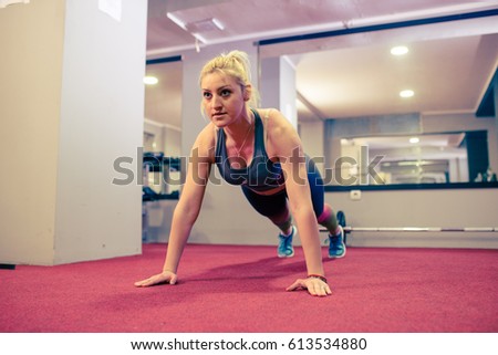 Blonde girl doing push ups at gym