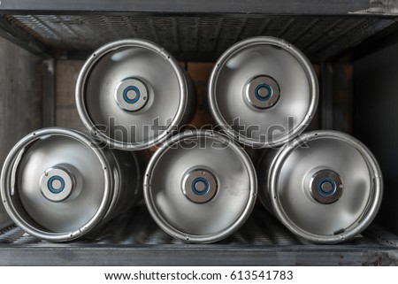 Metal beer kegs lie in a row on the shelf Royalty-Free Stock Photo #613541783