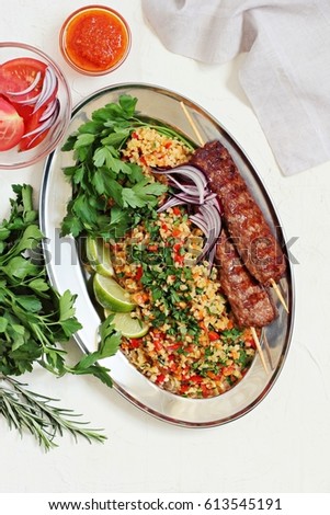 Kebab and tabbouleh.Bulgur salad with  meat kebab of minced beef or lamb with vegetables and herbs .  Top view