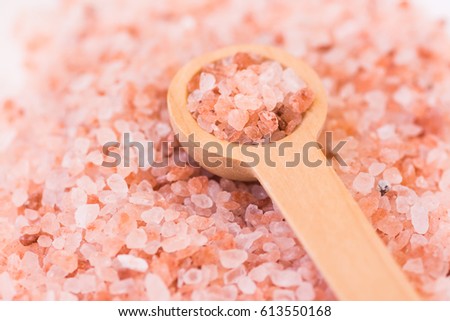 Scattered pink Himalayan salt, wooden spoon, spa, health, wellness concept, macro. 