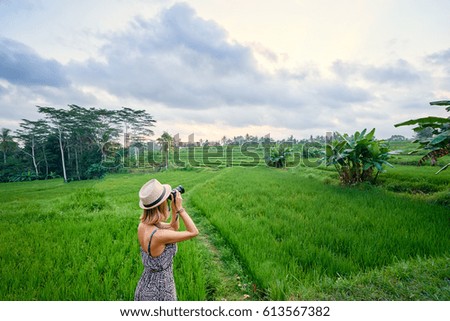 Tourism and travel. Young woman in hat taking photo of beautiful rice field landscape.